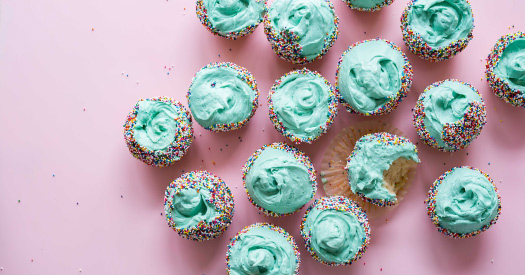 Aerial view of a cluster of vanilla cupcakes with blue frosting with sugar that causes cavities